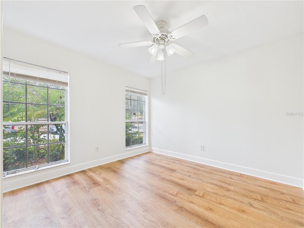 An empty bedroom features white walls, light wood-look flooring, two windows, and a ceiling fan — 10553 EGRET HAVEN LANE, RIVERVIEW, FL