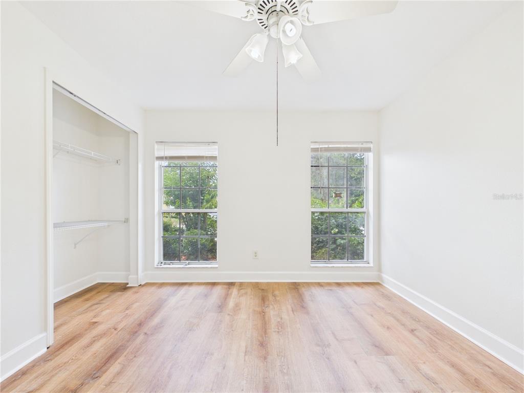 An empty bedroom features light wood-look flooring, white walls, a ceiling fan, and two windows — 10553 EGRET HAVEN LANE, RIVERVIEW, FL