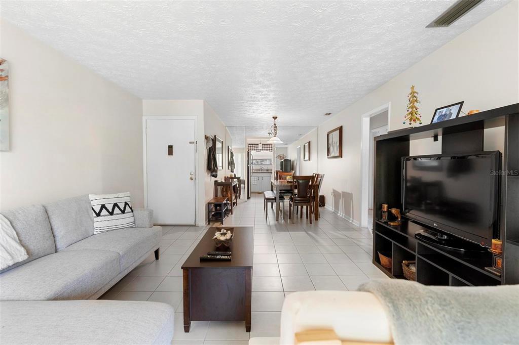 A living room with a grey sofa, coffee table, and television leads into a dining area — 4376 LAKE UNDERHILL ROAD UNIT C, ORLANDO, FL