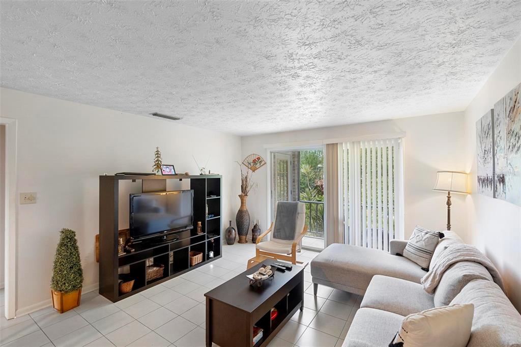 A living room features white tile floors, a dark entertainment center, and a gray sectional sofa — 4376 LAKE UNDERHILL ROAD UNIT C, ORLANDO, FL