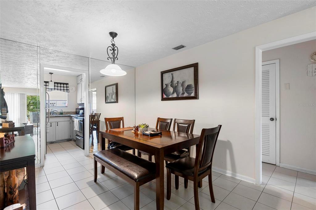 A dining room features a wooden table with a bench and chairs under a pendant light — 4376 LAKE UNDERHILL ROAD UNIT C, ORLANDO, FL