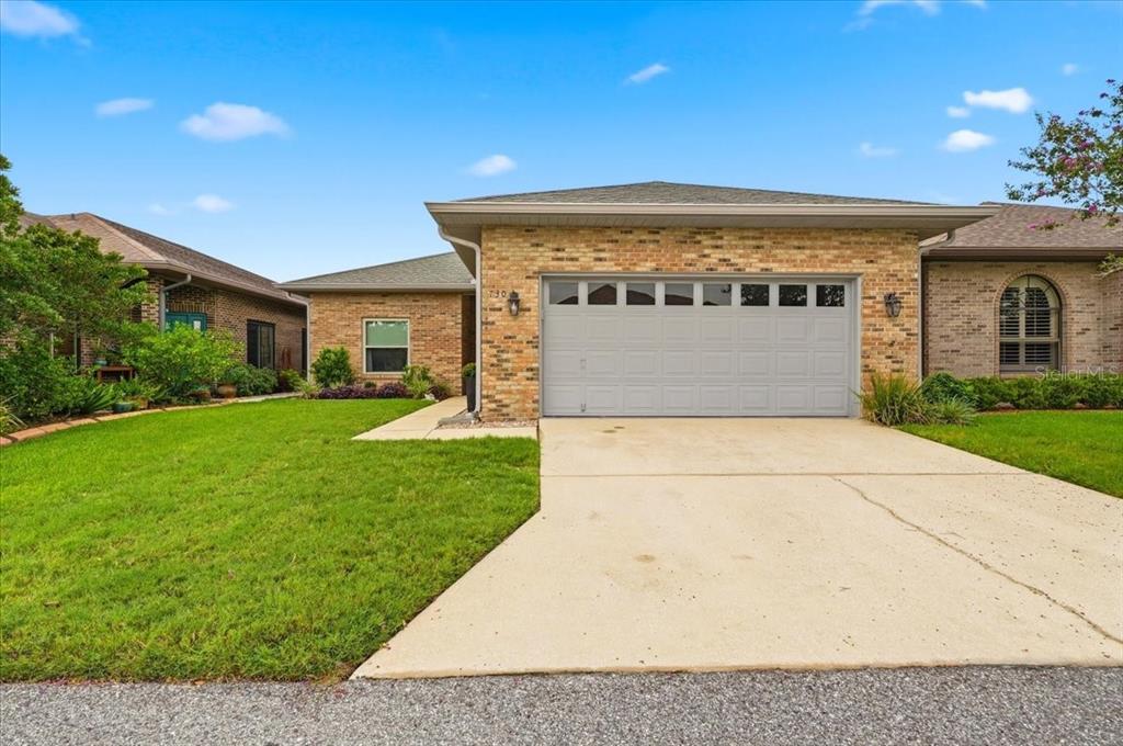A single-story brick house with a two-car garage and a concrete driveway — 730 MARTINIQUE CIRCLE, LAKELAND, FL