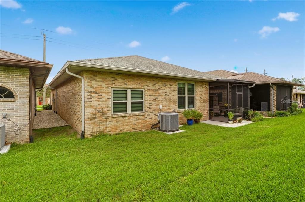 The exterior of a brick house features a screened-in porch and a central air conditioning unit — 730 MARTINIQUE CIRCLE, LAKELAND, FL