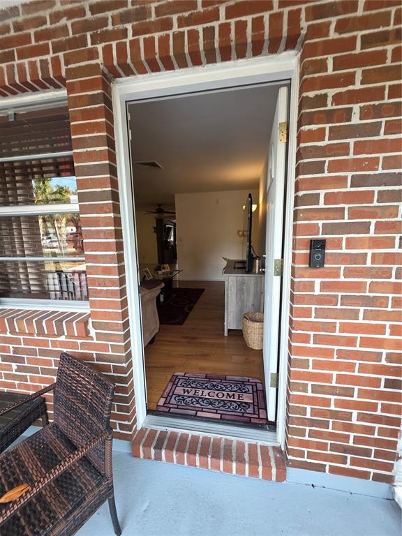 A view through an open front door reveals a living room with wood flooring — 8088 CLIPPER COURT, SPRING HILL, FL