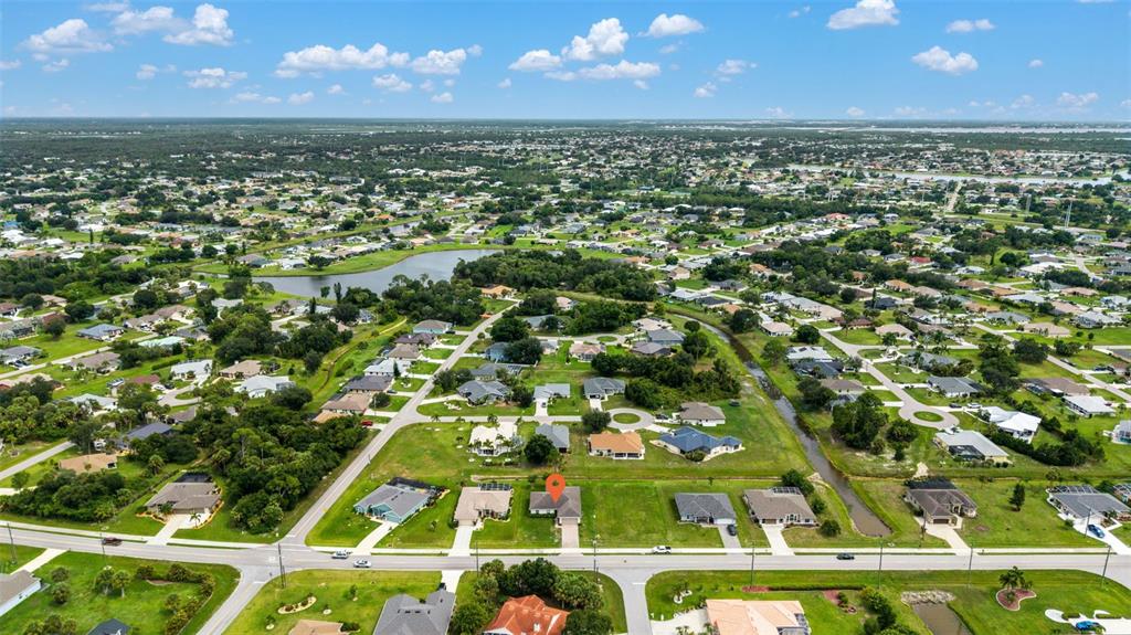 An aerial view shows a residential neighborhood with a marked house on a corner lot — 25599 DEEP CREEK BOULEVARD, PUNTA GORDA, FL