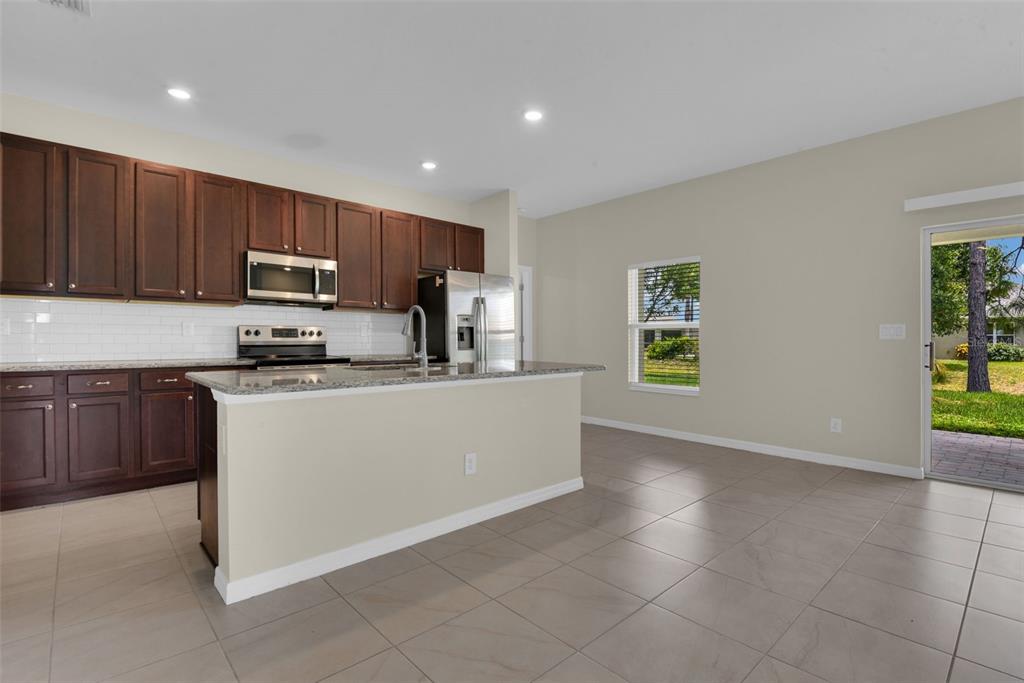 A kitchen features dark wood cabinets, granite countertops, a kitchen island, and tile flooring — 25599 DEEP CREEK BOULEVARD, PUNTA GORDA, FL