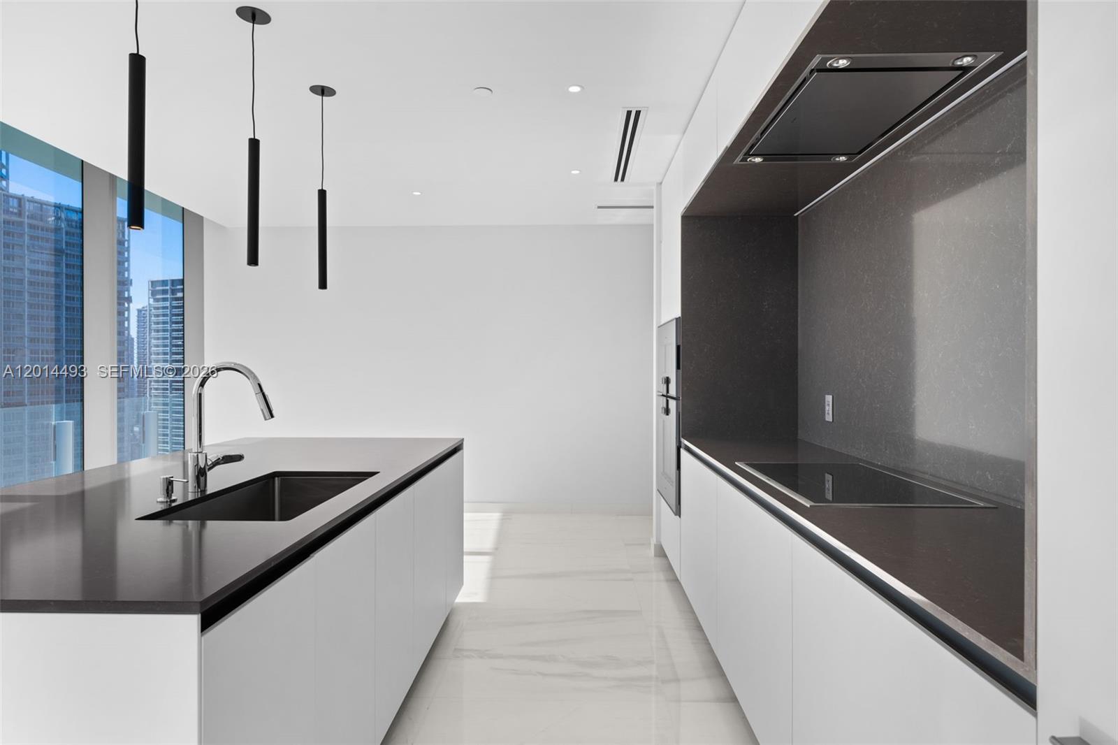 A modern kitchen features a white island, dark countertops, and floor-to-ceiling windows with city views — 300 Biscayne Blvd Way # 3801, Miami FL 33131, MIAMI, FL