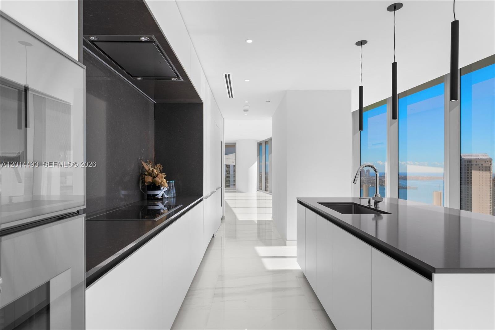 A modern kitchen features white cabinetry, dark countertops, a central island, and floor-to-ceiling windows — 300 Biscayne Blvd Way # 3801, Miami FL 33131, MIAMI, FL