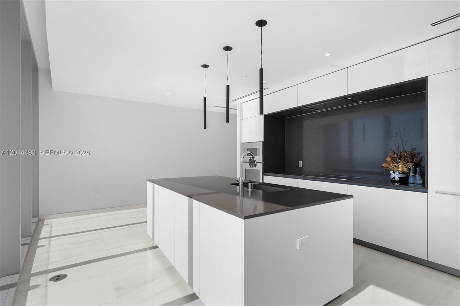 A modern kitchen features a white island with a dark countertop and matching cabinetry — 300 Biscayne Blvd Way # 3801, Miami FL 33131, MIAMI, FL