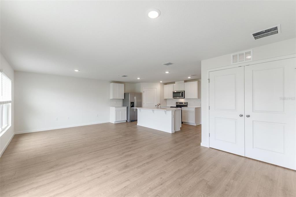 An open-concept living area features light wood-look flooring, white walls, and a modern kitchen — 904 E MICHIGAN AVENUE, DELAND, FL