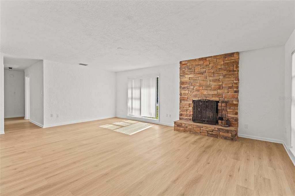 A living room with light wood flooring, white walls, and a stone fireplace — 2588 COLORADO STREET, SARASOTA, FL