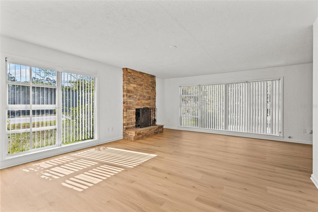 A living room features light wood flooring, white walls, a stone fireplace, and large windows — 2588 COLORADO STREET, SARASOTA, FL