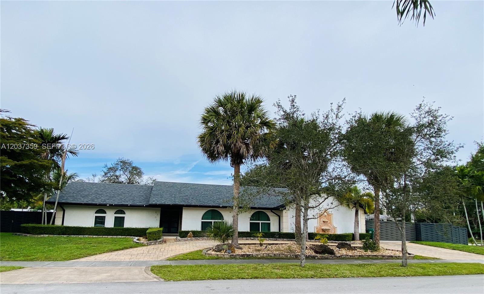A single-story house with a dark shingled roof, arched windows, and palm trees — 8701 SW 191st St, Cutler Bay FL 33157, CUTLER BAY, FL