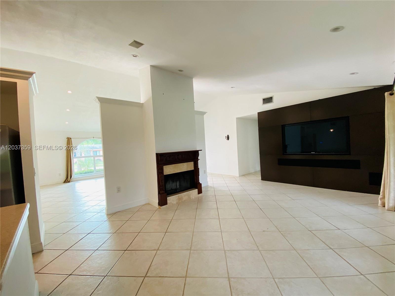 A living room features a fireplace, a dark accent wall with a television, and tile flooring — 8701 SW 191st St, Cutler Bay FL 33157, CUTLER BAY, FL