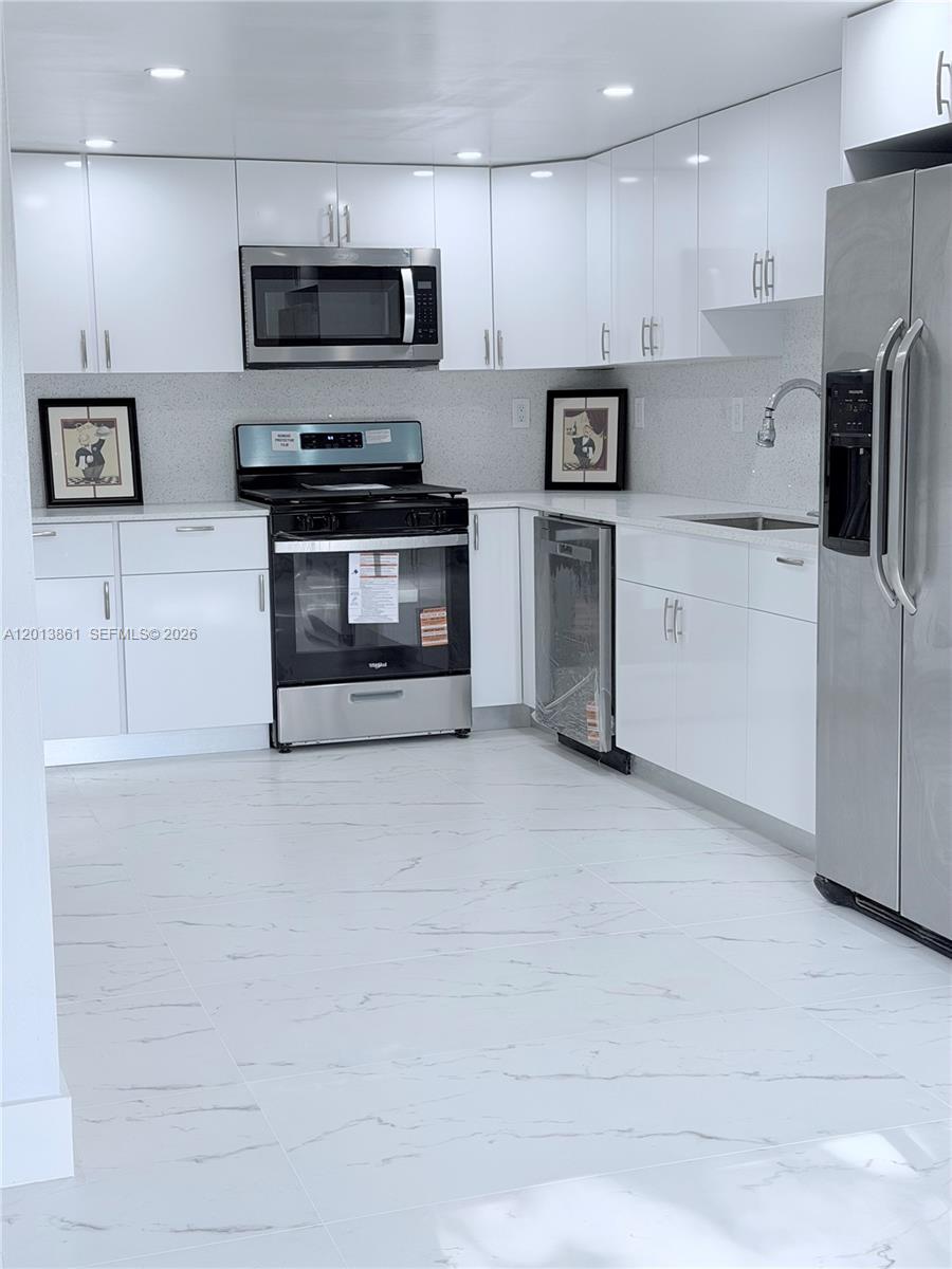 A modern kitchen features white cabinets, stainless steel appliances, and white marble-patterned tile flooring — 7024 SW 114th Pl # 52, Miami FL 33173, MIAMI, FL