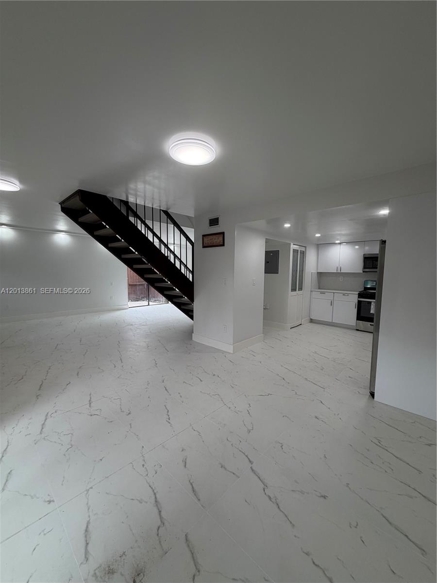 An open-concept living area features white marble-look tile flooring and a dark metal staircase — 7024 SW 114th Pl # 52, Miami FL 33173, MIAMI, FL
