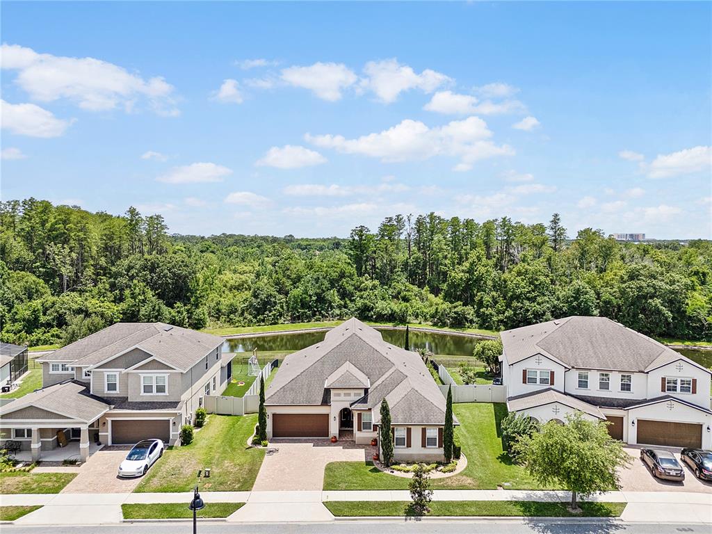 An aerial view shows three suburban houses with paved driveways facing a pond and trees — 1692 HIGHBANKS CIRCLE, WINTER GARDEN, FL