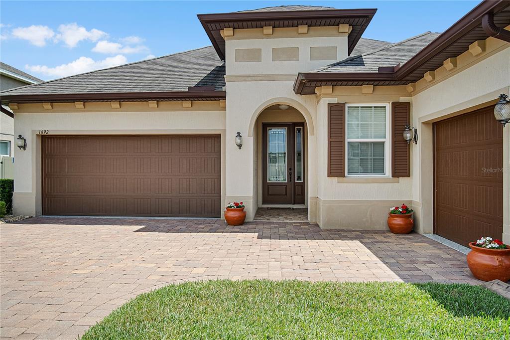 A single-story house exterior features a paved driveway, two garage doors, and a front entrance — 1692 HIGHBANKS CIRCLE, WINTER GARDEN, FL