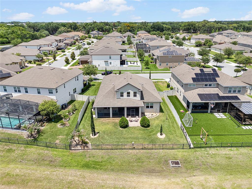An aerial view shows suburban houses with fenced backyards and a grassy field nearby — 1692 HIGHBANKS CIRCLE, WINTER GARDEN, FL