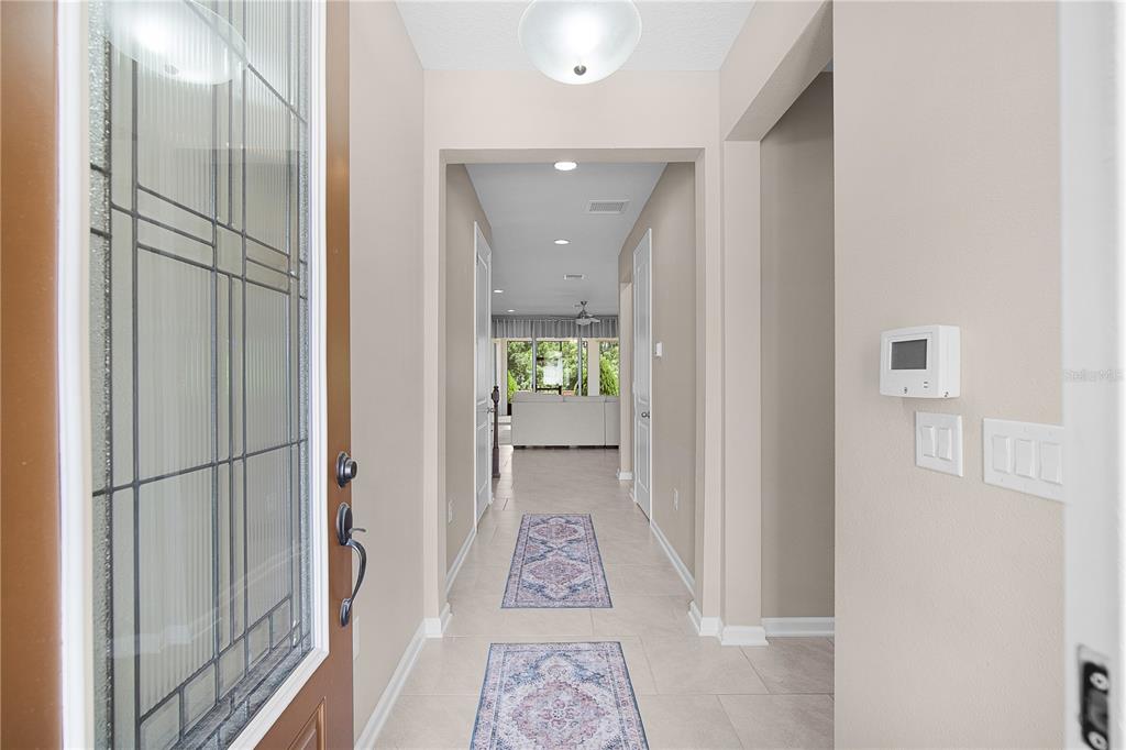 A bright entryway features a glass-paneled front door, tile flooring, and a long hallway — 1692 HIGHBANKS CIRCLE, WINTER GARDEN, FL