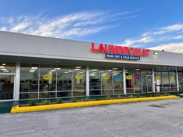 The exterior of a commercial laundromat building features large glass windows and a prominent red sign — 600 S PARK AVENUE, TITUSVILLE, FL