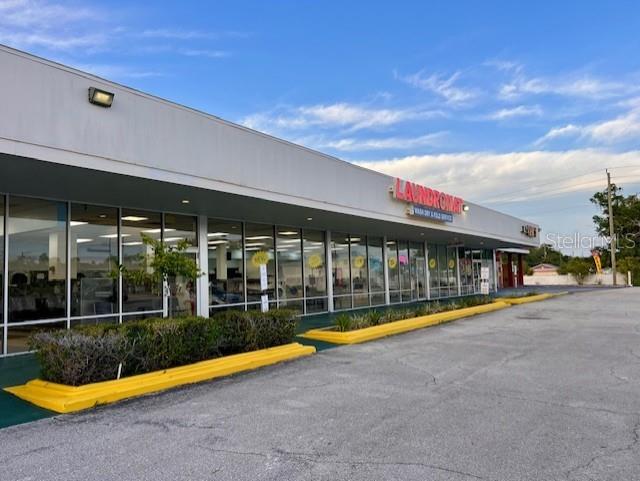 A low-rise commercial building features a laundromat with large glass windows and yellow curbs — 600 S PARK AVENUE, TITUSVILLE, FL