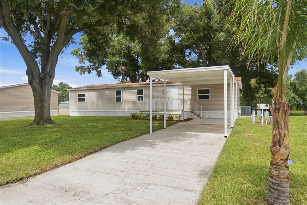 A single-story manufactured home with a concrete driveway, carport, and a small front porch — 16918 SUGAR BERRY LANE, MONTVERDE, FL