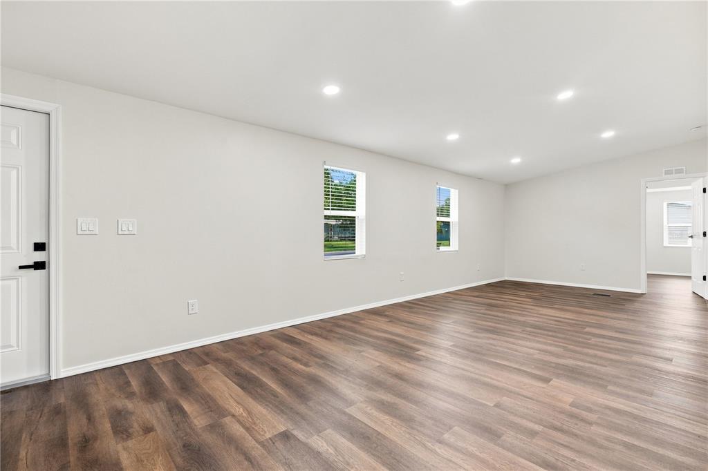 An empty room features light-colored walls, recessed lighting, and dark wood-look flooring — 16918 SUGAR BERRY LANE, MONTVERDE, FL