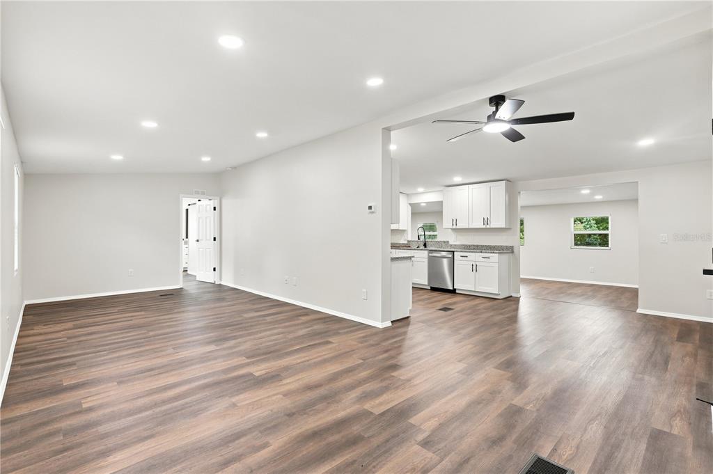 An open-concept living area features wood-look flooring, recessed lighting, and a kitchen with white cabinets — 16918 SUGAR BERRY LANE, MONTVERDE, FL