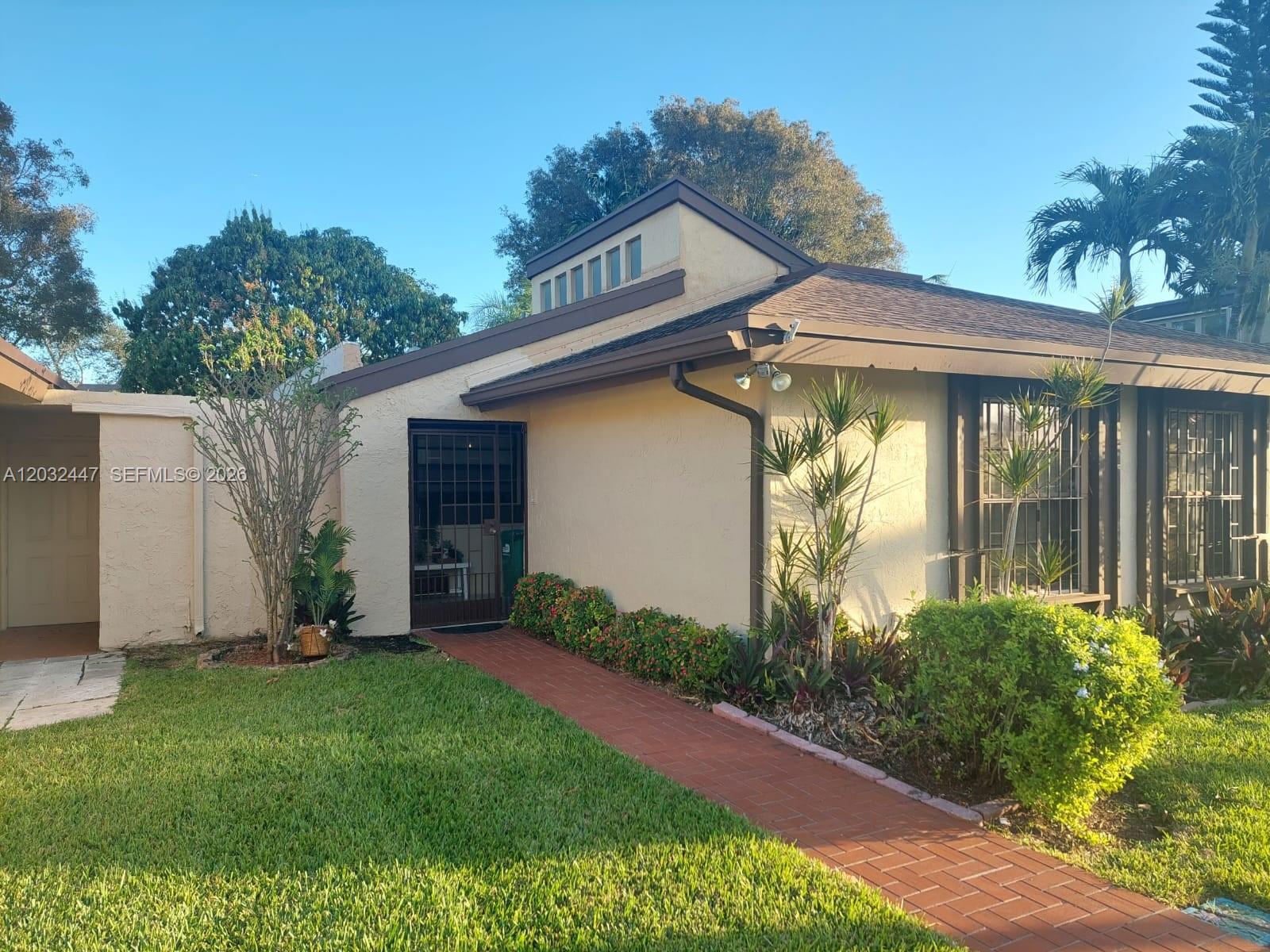 A single-story house features a brick walkway leading to a gated entrance and large windows — 9119 SW 129th Ln # 0, Miami FL 33176, MIAMI, FL