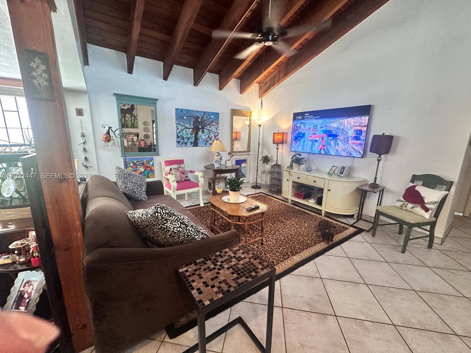A living room features a vaulted wood-beamed ceiling, tile flooring, and a leopard-print area rug — 9119 SW 129th Ln # 0, Miami FL 33176, MIAMI, FL
