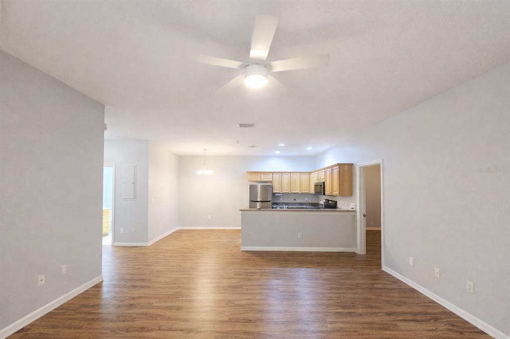 An open-concept living area features wood-look flooring, a ceiling fan, and a kitchen with cabinets — 2549 RIVER PRESERVE COURT, BRADENTON, FL