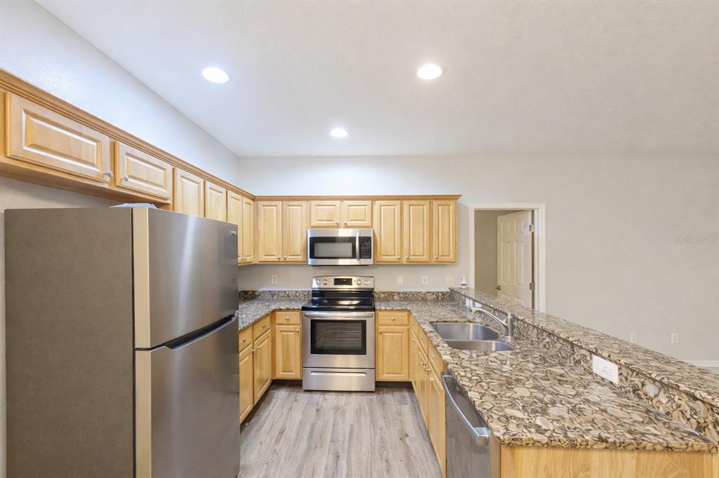 A kitchen with light wood cabinets, granite countertops, and stainless steel appliances — 2549 RIVER PRESERVE COURT, BRADENTON, FL