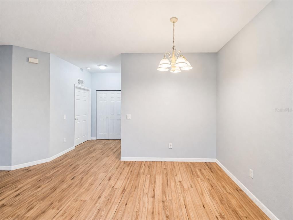A dining area with light wood-look flooring, a central chandelier, and white interior doors — 2549 RIVER PRESERVE COURT, BRADENTON, FL