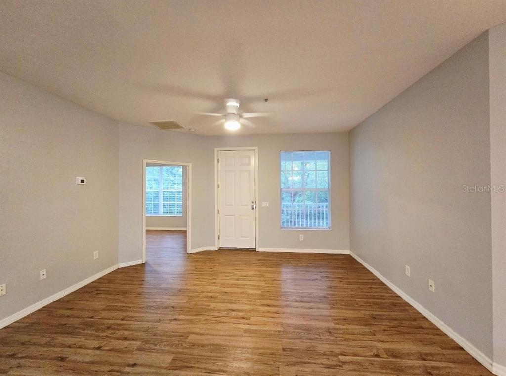 An empty room with light gray walls, wood-look flooring, a ceiling fan, and two windows — 2549 RIVER PRESERVE COURT, BRADENTON, FL