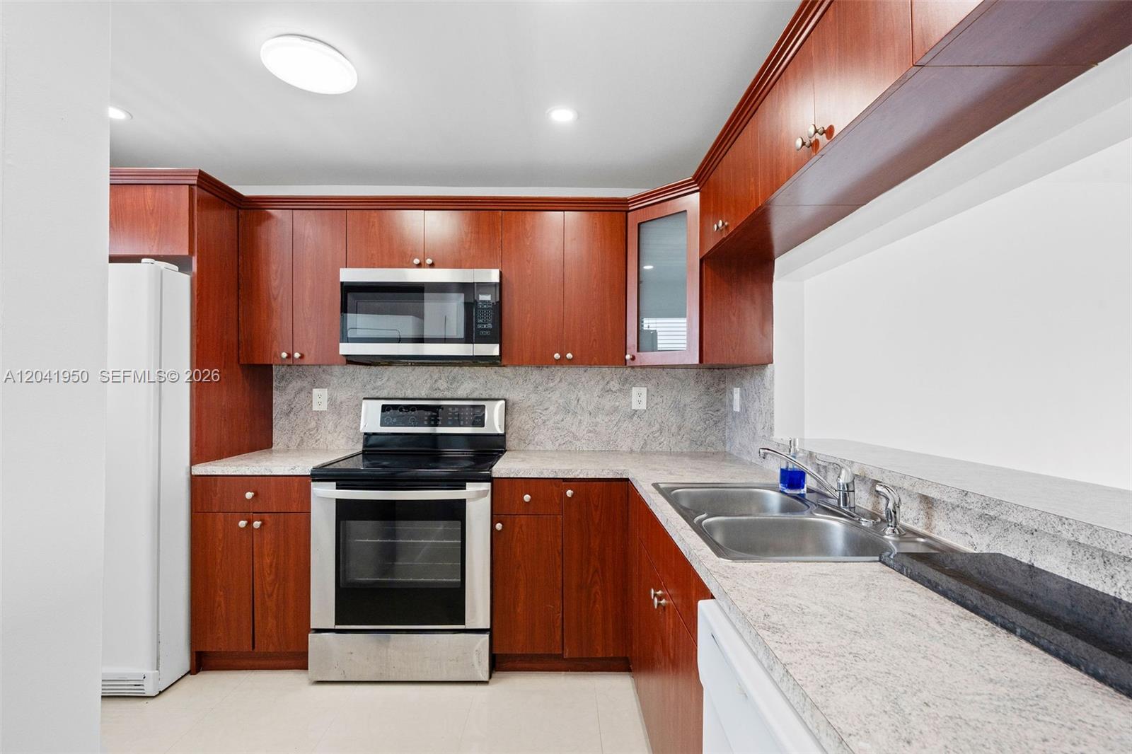 A kitchen features cherry wood cabinets, stainless steel appliances, and speckled granite countertops — 10288 NW 9th St Cir # 501, Miami FL 33172, MIAMI, FL