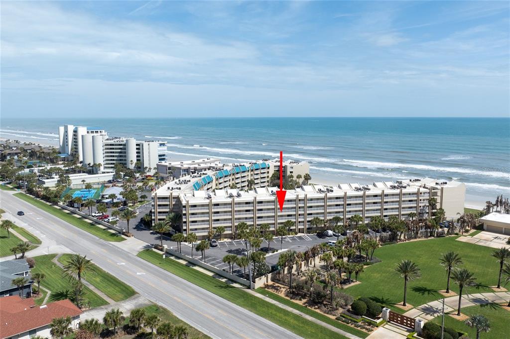 An aerial view shows a multi-story beachfront condominium complex with a red arrow pointing downward — 4501 S ATLANTIC AVENUE UNIT 209, NEW SMYRNA BEACH, FL