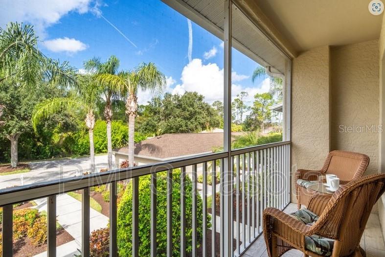 A screened-in balcony features two wicker chairs overlooking a parking area and palm trees — 5320 HYLAND HILLS AVENUE UNIT 2225, SARASOTA, FL