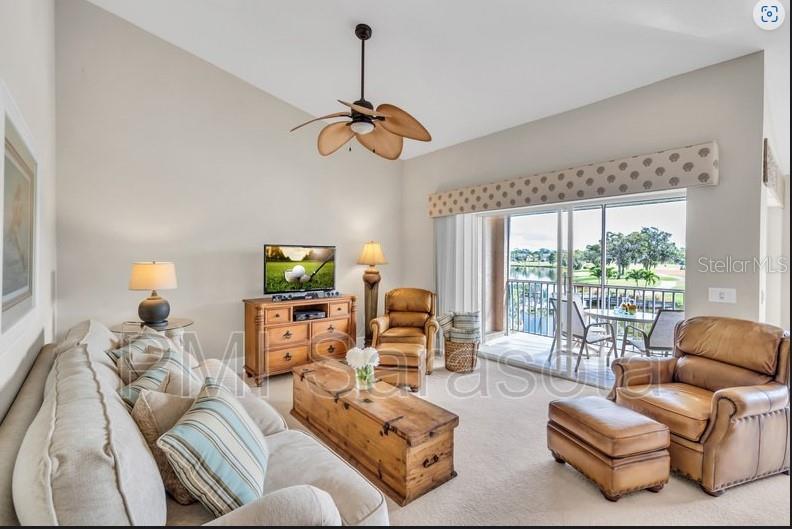 A living room features a vaulted ceiling, a ceiling fan, and a balcony overlooking water — 5320 HYLAND HILLS AVENUE UNIT 2225, SARASOTA, FL