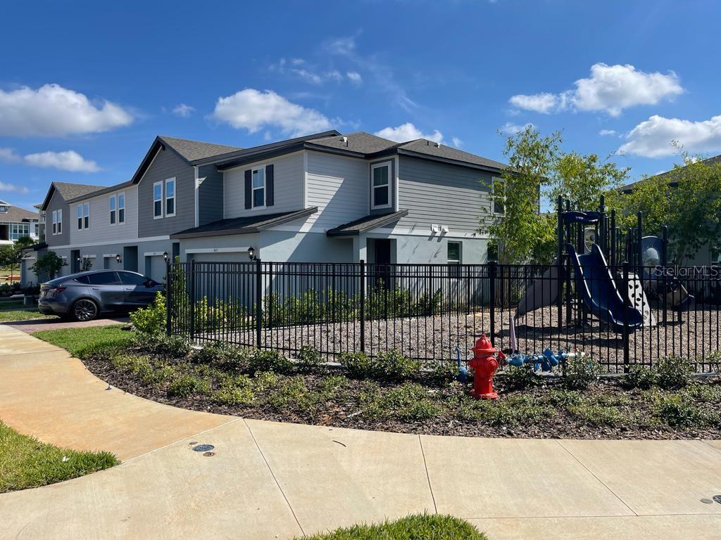 A two-story townhouse exterior features a fenced playground area and a parked gray car — 407 LEGACY LOOP, DAVENPORT, FL