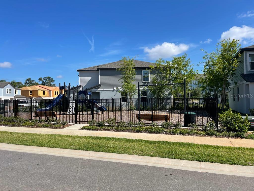 A fenced-in playground with slides and benches sits in front of a two-story house — 407 LEGACY LOOP, DAVENPORT, FL
