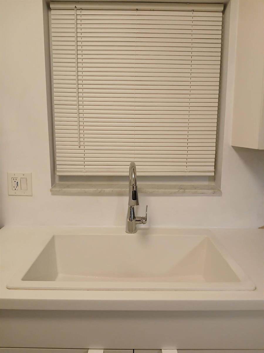 A white kitchen sink with a chrome faucet is positioned beneath a window with blinds — 721 Lori Drive # 309, Palm Springs FL 33461, PALM SPRINGS, FL