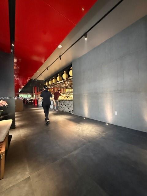 A person walks through a modern restaurant hallway with a red ceiling and concrete walls — University Dr, Coral Springs FL 33071, CORAL SPRINGS, FL