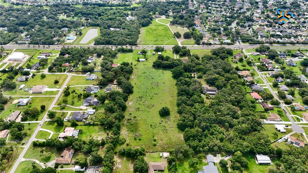 An aerial view shows a large, undeveloped grassy lot surrounded by residential houses and trees — 1886 PLEASANT HILL ROAD, KISSIMMEE, FL