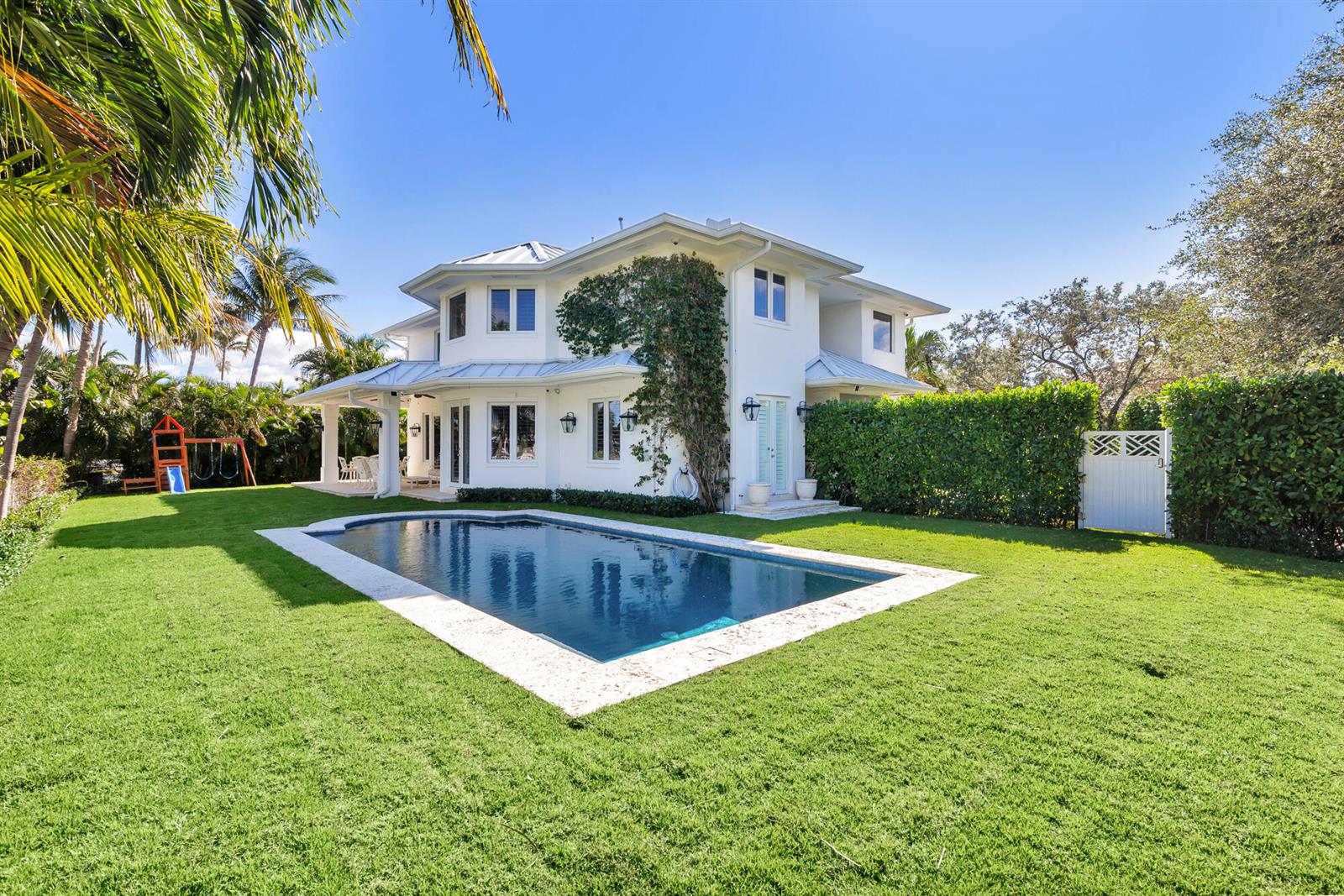 A two-story white house features a swimming pool in a grassy backyard with palm trees — 2614 Furman Lane, FL 33460, FL