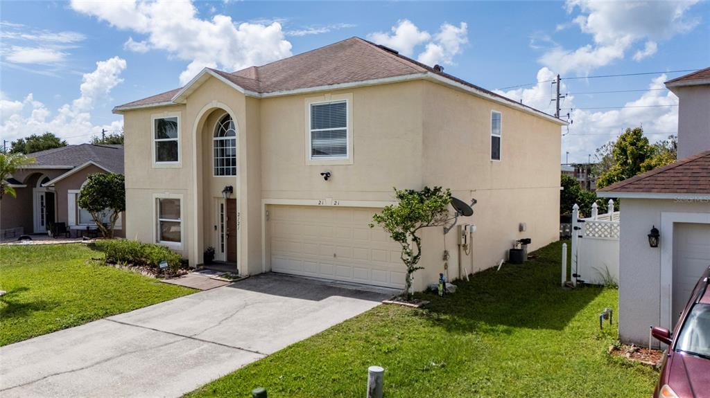 A two-story, beige stucco house with a two-car garage and a concrete driveway — 2121 BLACKSTONE LANDING DRIVE, KISSIMMEE, FL