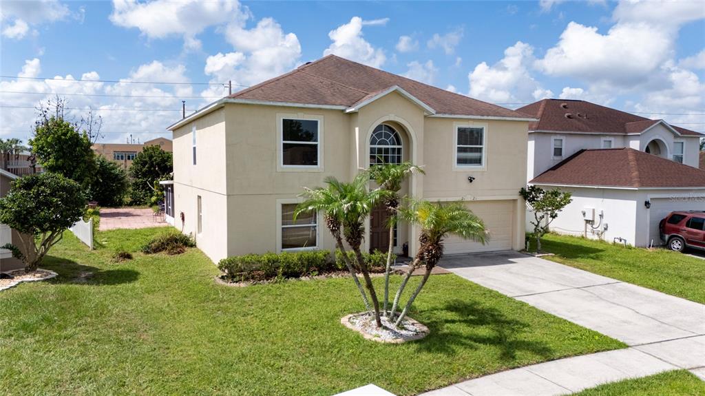 A two-story beige house with a brown roof, palm trees, and a concrete driveway — 2121 BLACKSTONE LANDING DRIVE, KISSIMMEE, FL