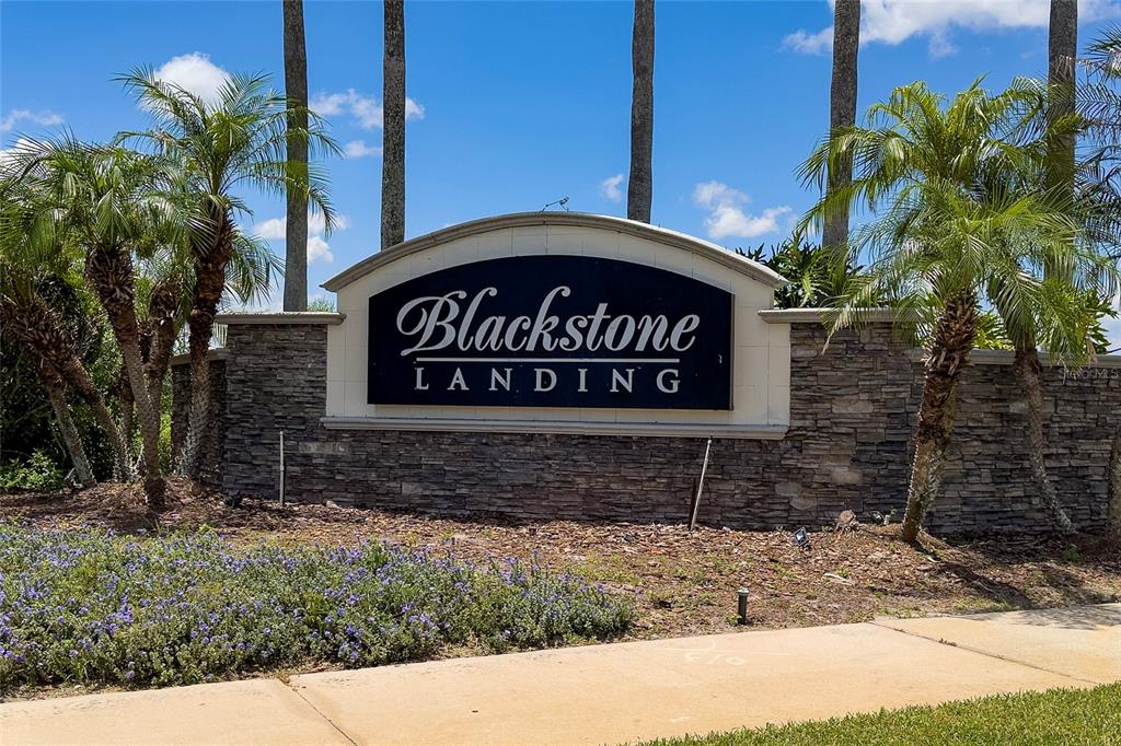 A stone monument sign for Blackstone Landing stands outdoors surrounded by palm trees and landscaping — 2121 BLACKSTONE LANDING DRIVE, KISSIMMEE, FL