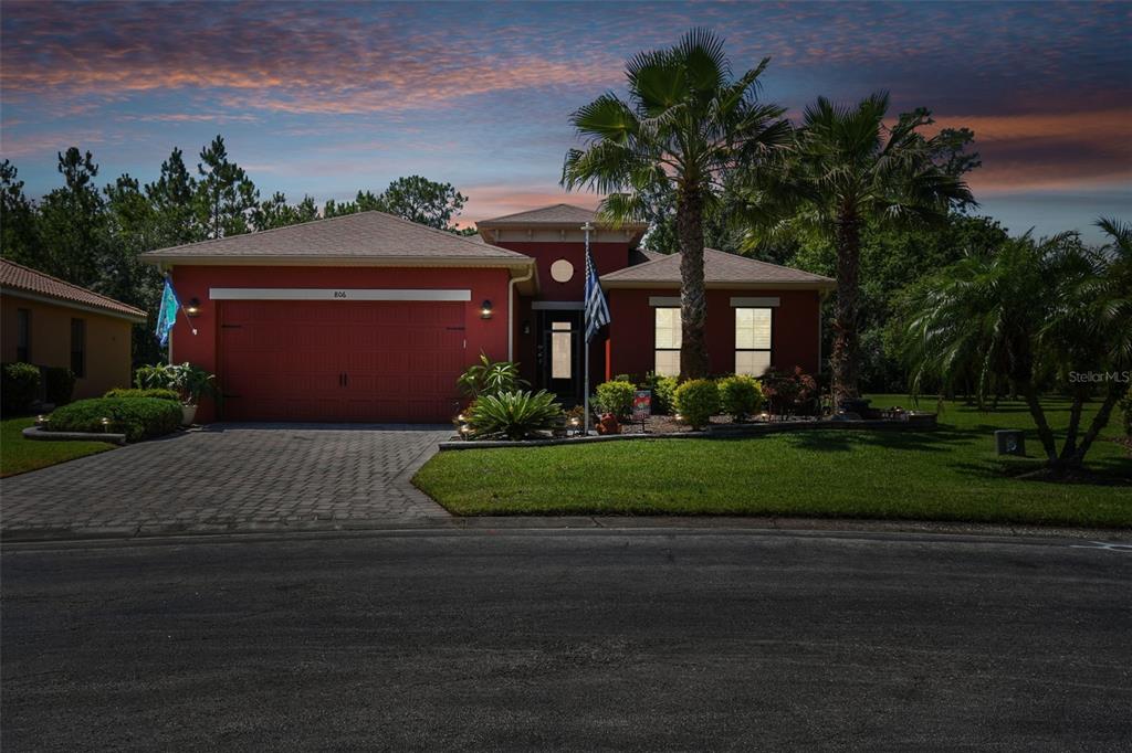 A red single-story house with a paved driveway and palm trees sits on a corner lot — 806 EBB TIDE LANE, KISSIMMEE, FL
