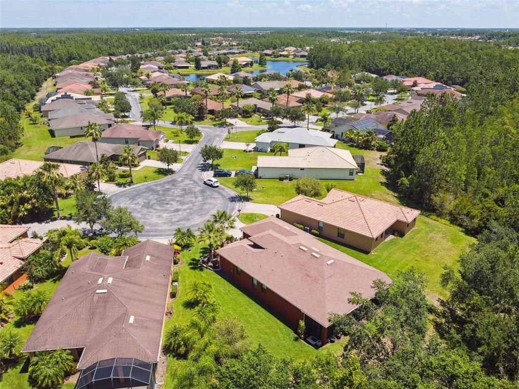 An aerial view of a suburban neighborhood featuring single-family homes, cul-de-sacs, and surrounding wooded areas — 806 EBB TIDE LANE, KISSIMMEE, FL